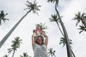 Mother holding her baby undeneath huge palm trees, Temae public beach, Moorea, French Polynesia Mother holding her baby undeneath huge palm trees, Temae public beach, Moorea, French Polynesia